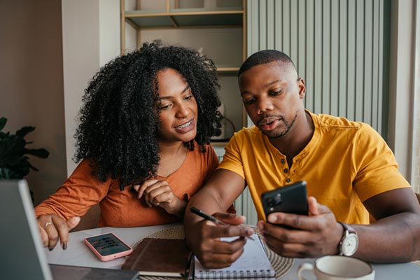 A couple at their kitchen table manage their finances.