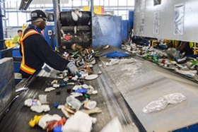 A worker sort recyclable materials on a conveyor belt