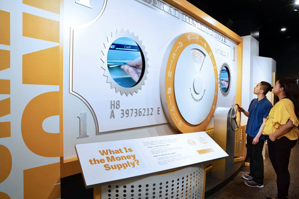 A man and woman spin the Journey of Money Wheel at the St. Louis Fed Economy Museum