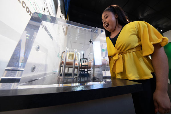 Excited woman attempts to lift gold bar at St. Louis Fed Economy Museum