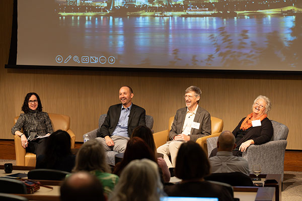 A group of people sitting in front of an audience, discussing a presentation.