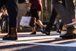 People briskly walking on a sidewalk.