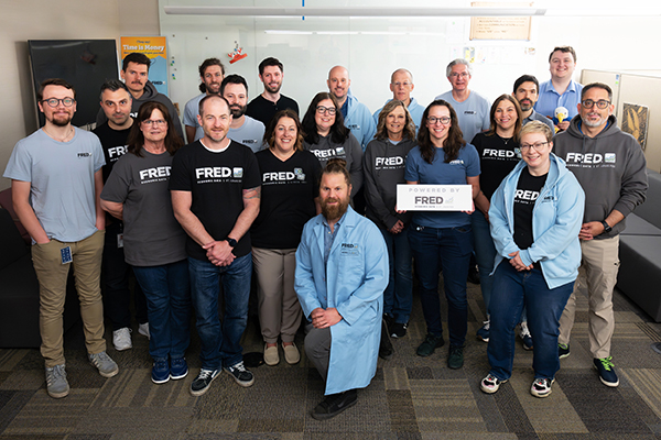 A group of people in ‘FRED’ shirts and apparel pose for a photo.