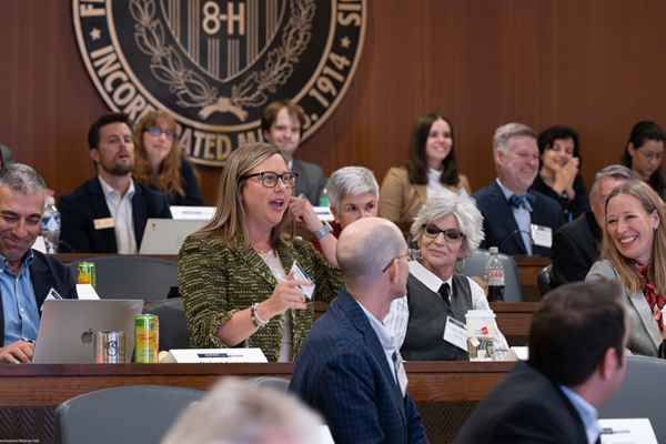 A woman speaks among a group of conference attendees.