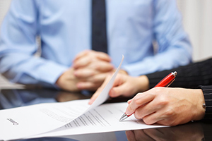 Woman is signing contract with business man in background