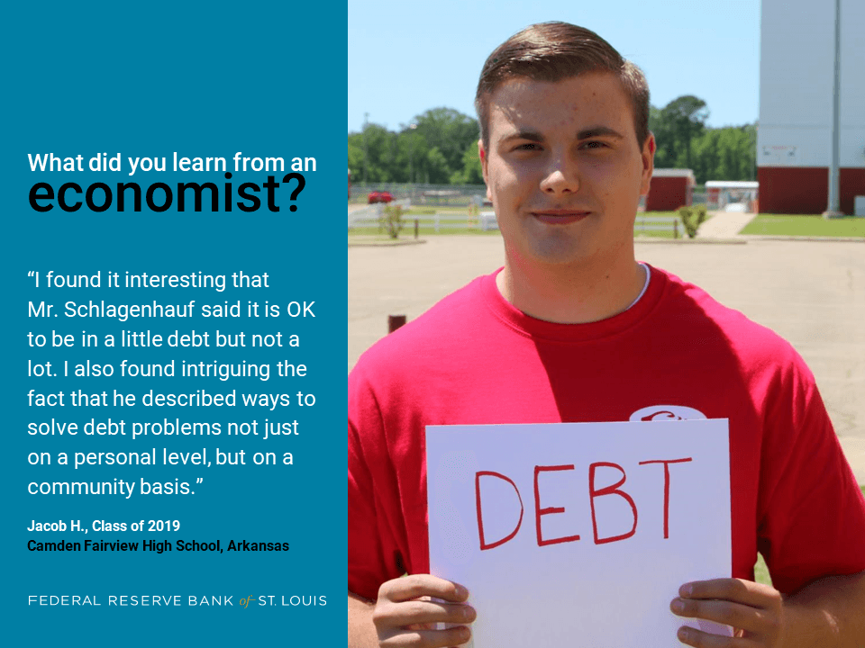 Jacob holds a sign outside his school. He is intrigued by solving debt on a community level