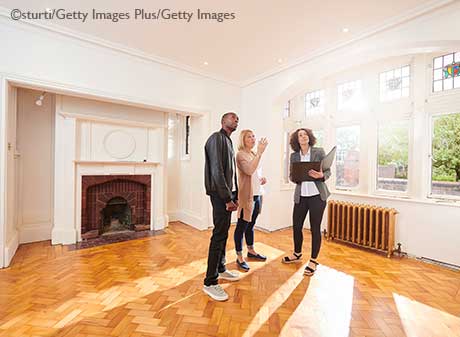 Young couple with Realtor viewing a spacious living room