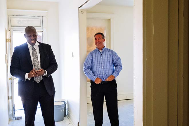 Andre Alexander and Jaycee Greene smile inside a home under renovation.