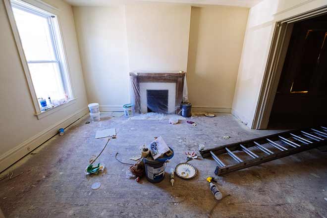 An empty family room with a ladder and cleaning supplies on the floor.