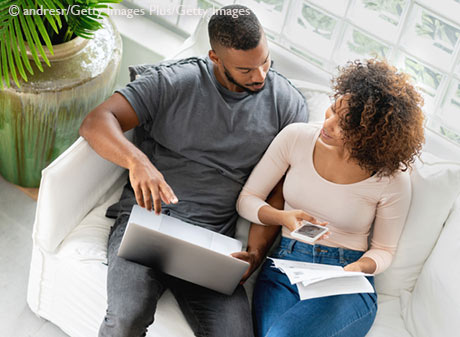 Stock photo African American couple paying bills online at home