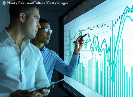 Businessmen studying graphs on an interactive screen in business meeting