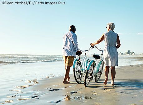 couple walking on beach with bikes