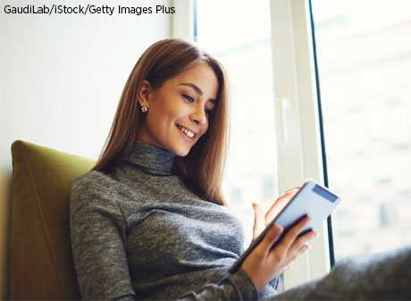 Young lady reading electronic device.