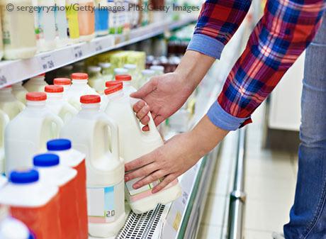 Stock image of a woman buying milk in a grocery store