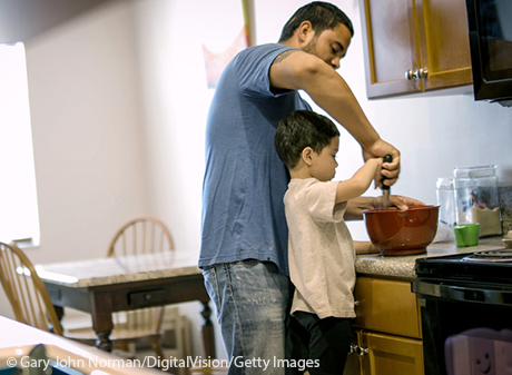 Young boy baking in kitchen with dad