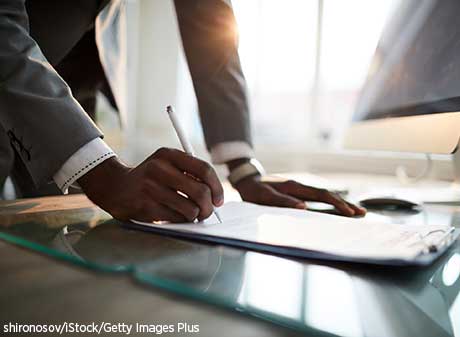 Black businessman signs a financial document.