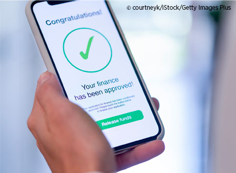 Woman holding a mobile phone with loan application approval.