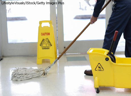 Janitor mops the floor near the entrance to an office building.