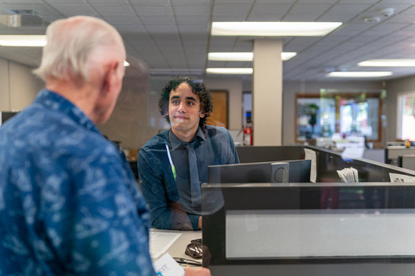 A bank teller talks with a customer seeking to make a transaction.