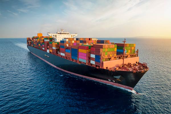An aerial view of a large, loaded containership at sea.
