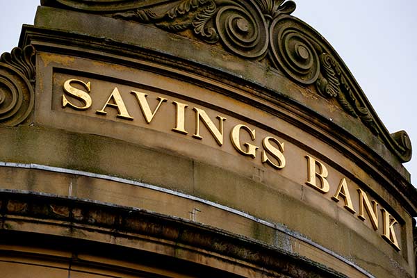 A close-up view of lettering on the façade of a classical stone building that reads ‘Savings Bank.’