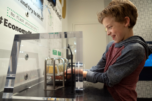 Kid attempting to lift the museum’s gold bar.