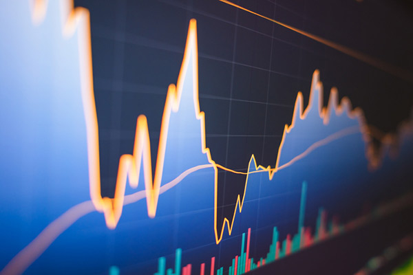 A computer monitor displays a chart with data rising and falling.