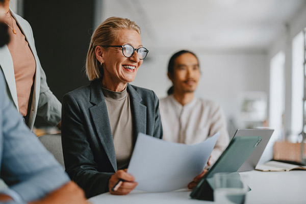 An older business executive leads a team in an office meeting.