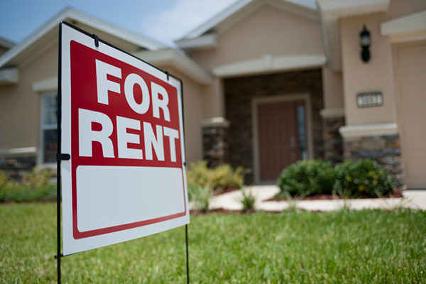 A 'for rent' sign sits on the front lawn of a single-family ranch-style home.