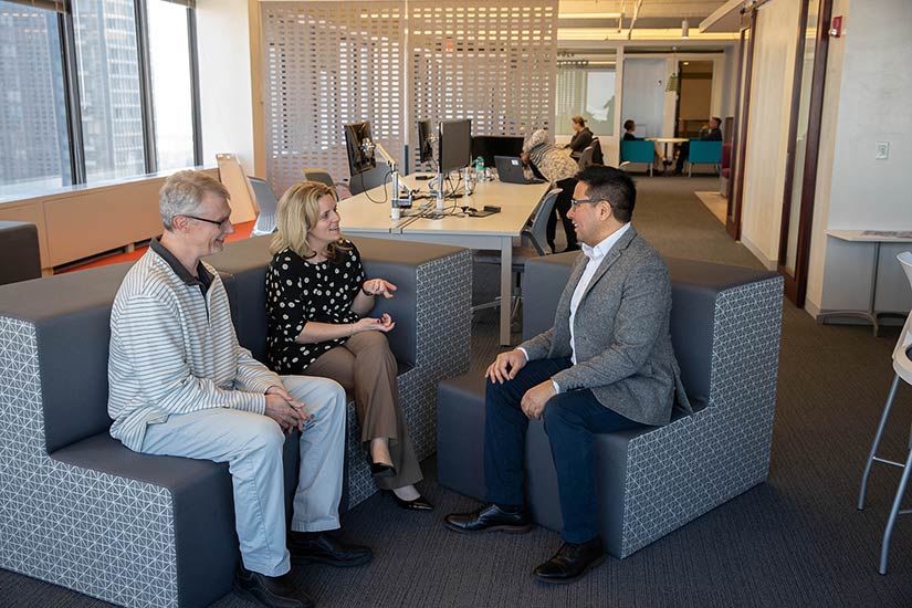 Two men and a women sit and have a conversation.