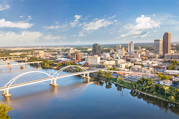 City skyline of Little Rock, Arkansas shows its river, bridge, and buildings.