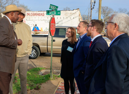 Group from the St. Louis Fed talk with two men near a stop sign.