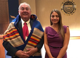 A man in a Native American shawl stands next to a young woman