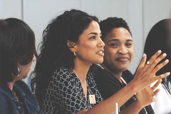 Woman speaks to a group gathered in a conference room.