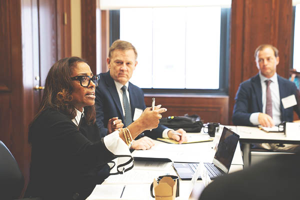Woman gestures and speaks while industry representatives look on.