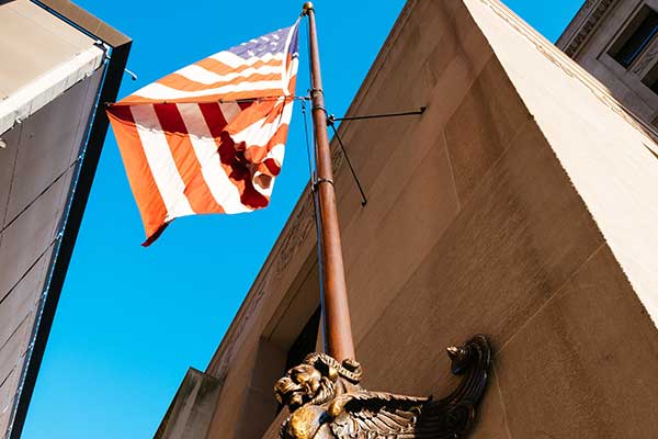 American flag outside St. Louis Fed building against a blue sky.