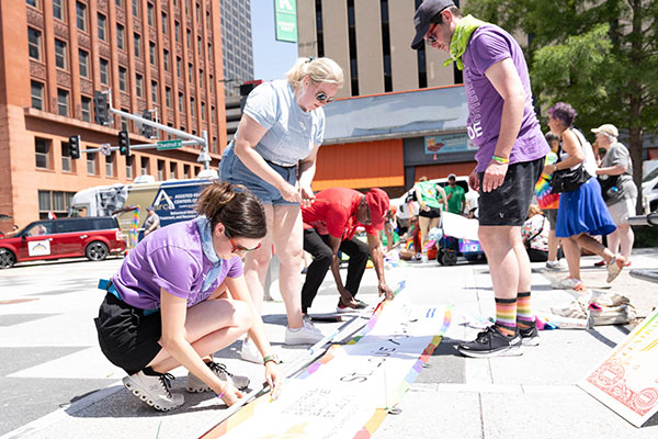 Employees lay out a banner on a sidewalk in downtown St. Louis.