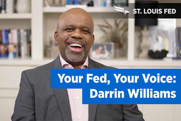 Darrin Williams smiles next to a 'Your Fed, Your Voice' banner.