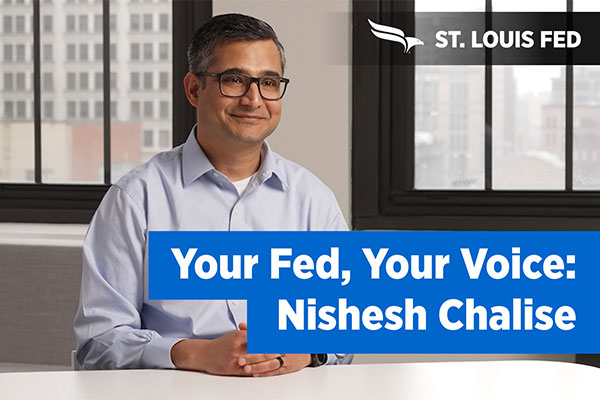 Nishesh Chalise smiles next to a 'Your Fed, Your Voice' banner.