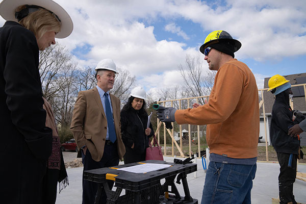 A group of people gather at a construction site reviewing construction plans