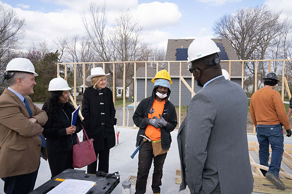 A group of people in construction hats gather at a construction site