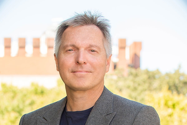A man in business casual attire is standing outside.