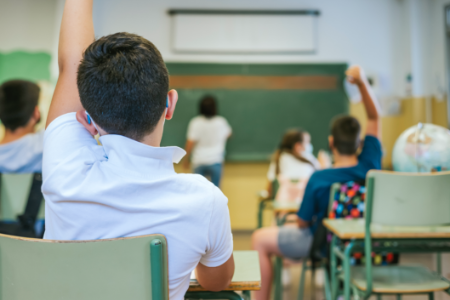 Young boy raises hand in classroom 