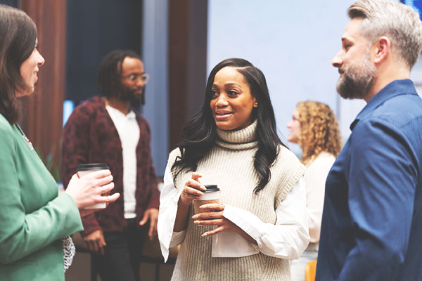 Group of employees converse as they stand together.