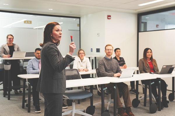 Woman presents in front of a classroom.