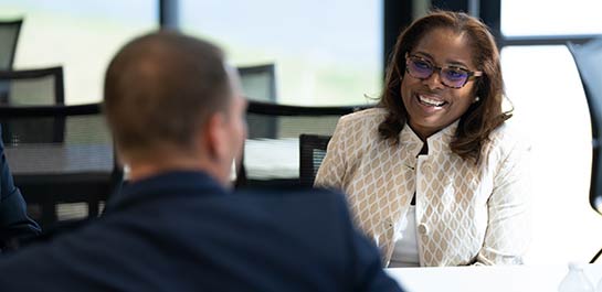 Woman seated, engaging in conversation with colleague