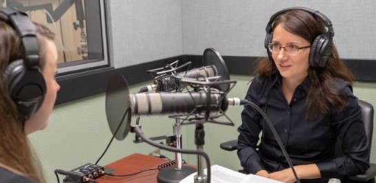 Two women seated in a podcast recording studio