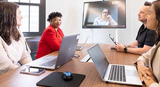 A man and two women sit in front of laptops.