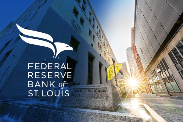 Bright sun shines through a plaza and illuminates the Federal Reserve Bank of St. Louis building.