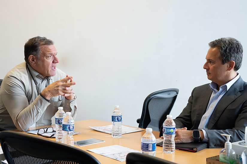 Musalem talks with a man seated with him at a conference table.